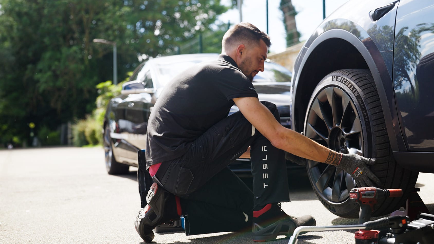 Male Tesla employee working on the tire of a Model Y on a public street