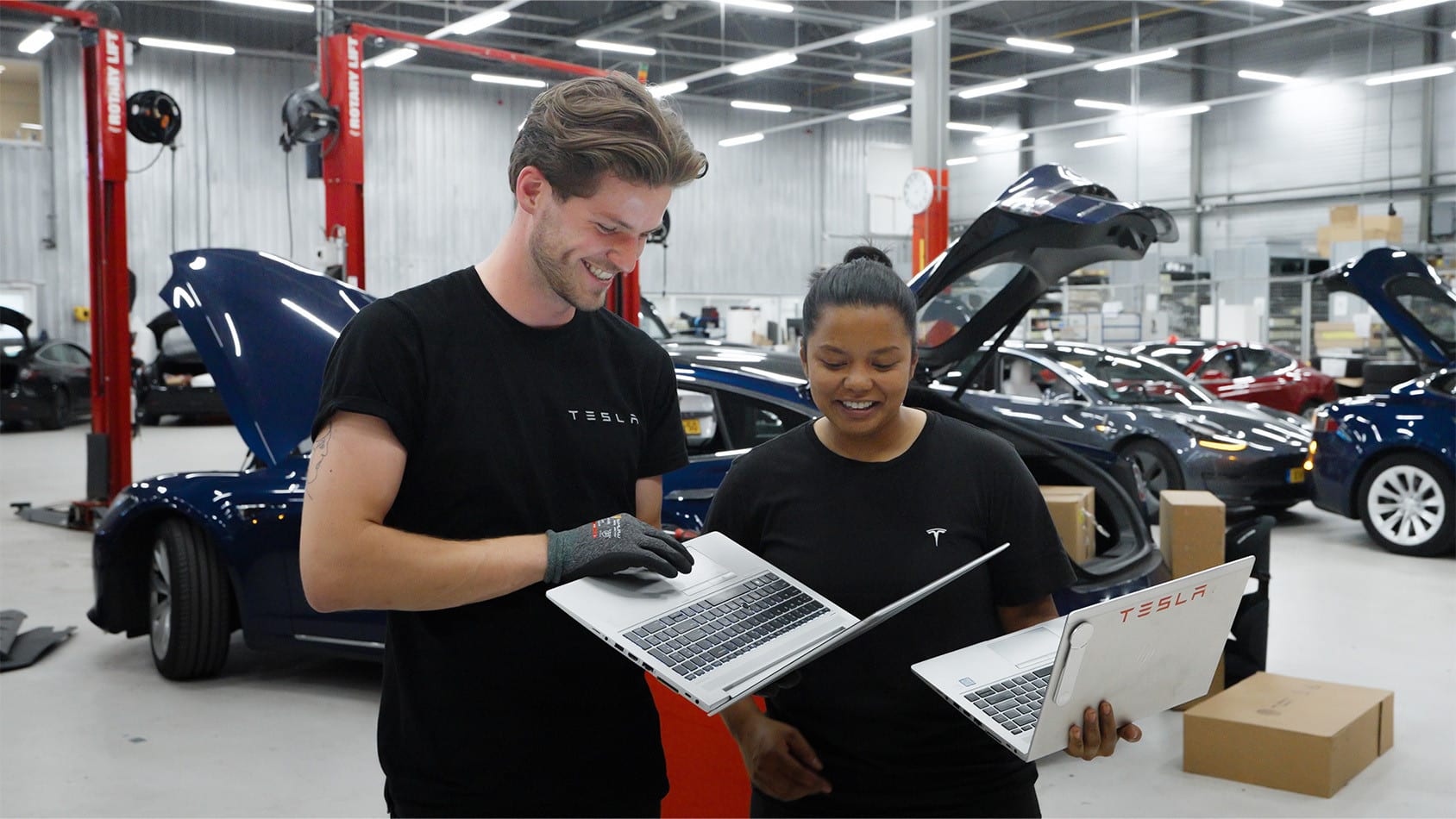 Tesla service employees working together on their laptops in a workshop