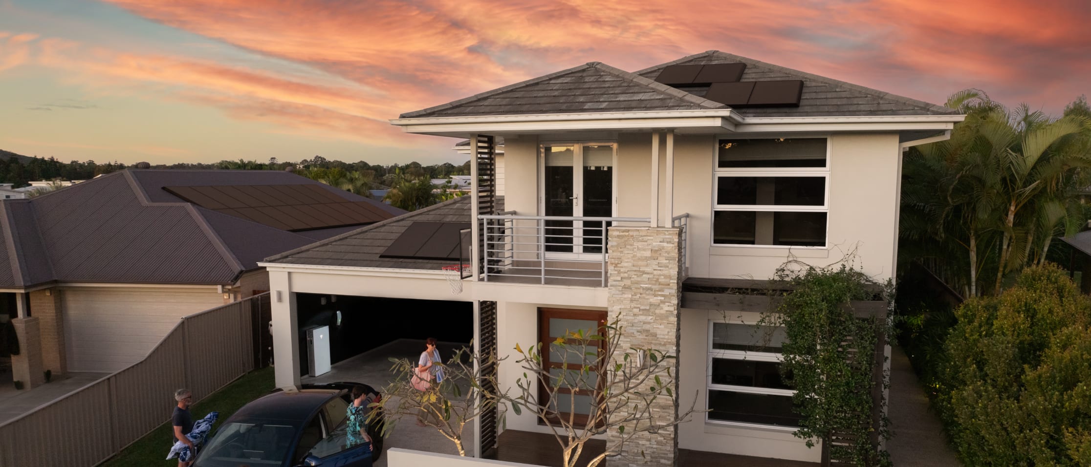 Modern home With Solar Panels and red Model S parked outside