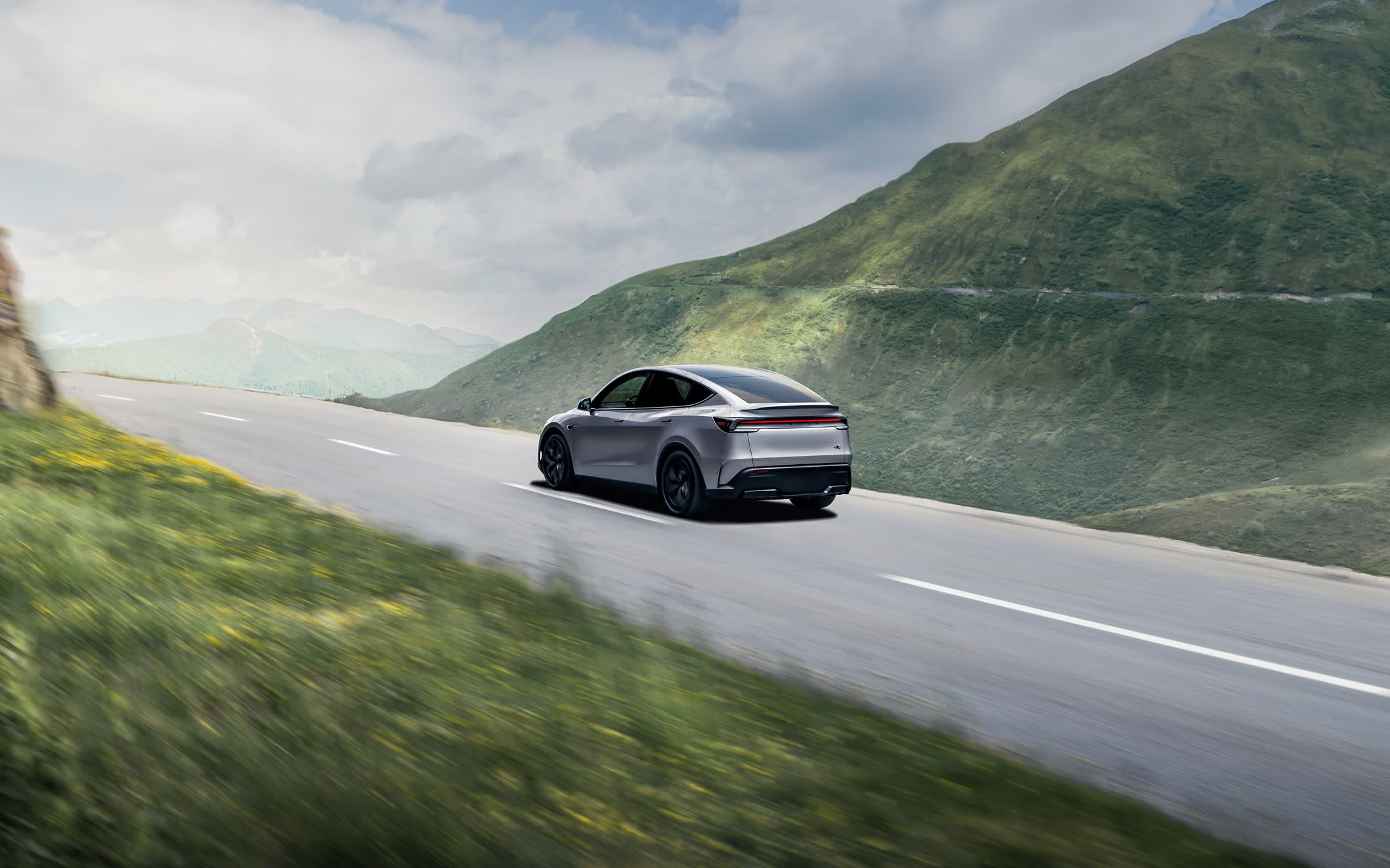 Quicksivler Model Y driving on the highway by the mountains