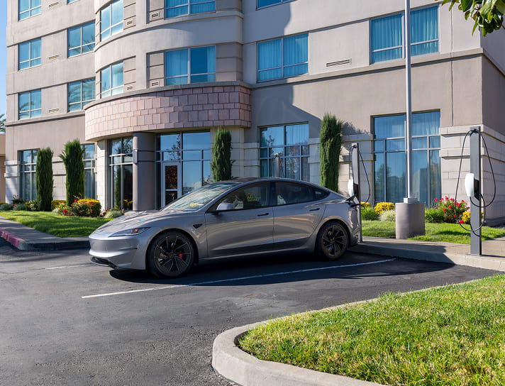 A Quicksilver Model 3 charging at Wall Connector surrounded by industrial buildings