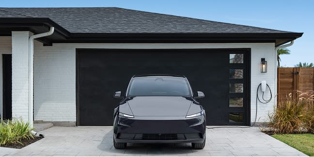 Black Model Y parked in front of a garage
