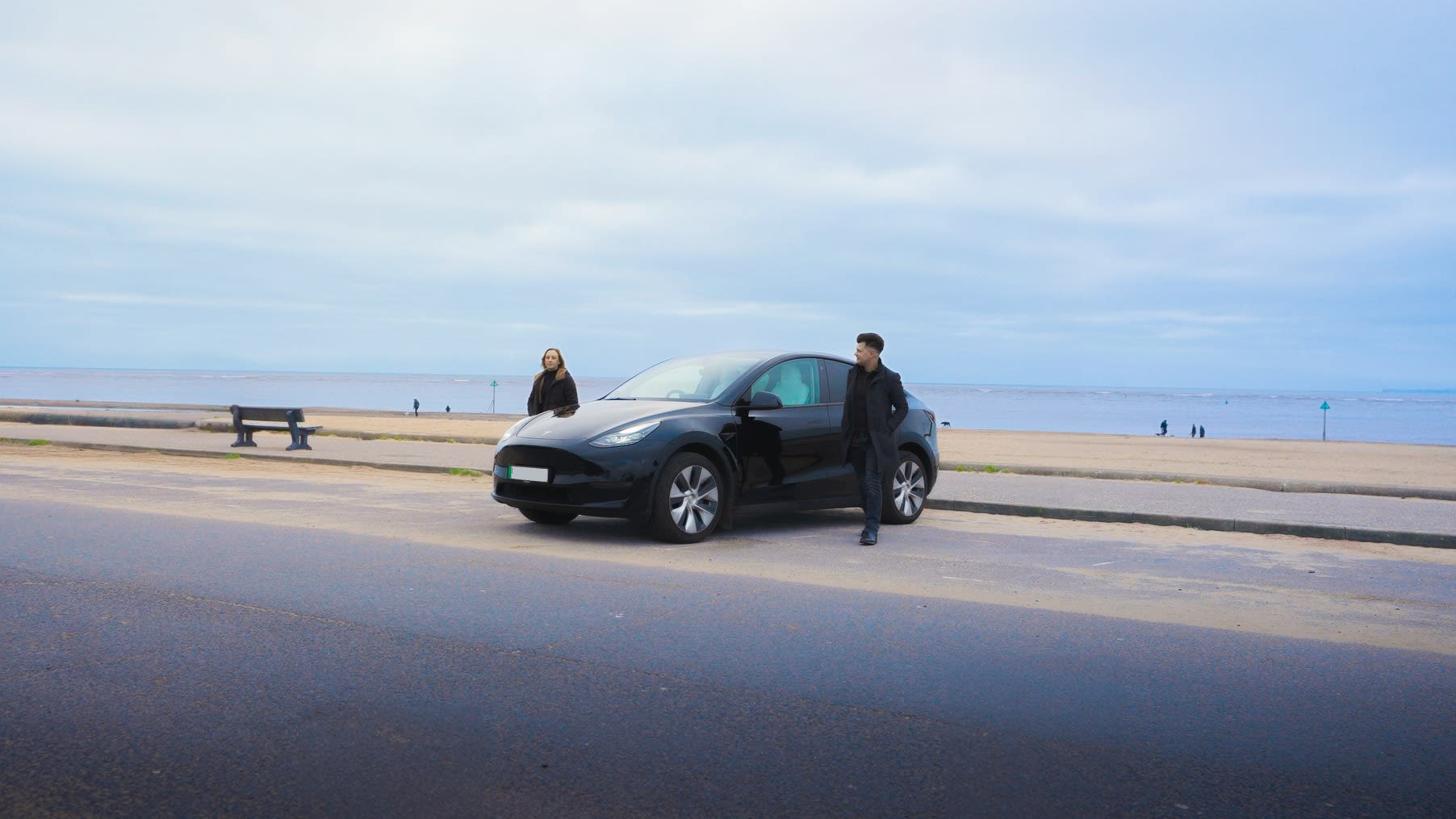 A Diamond Black Model Y parked by the beach