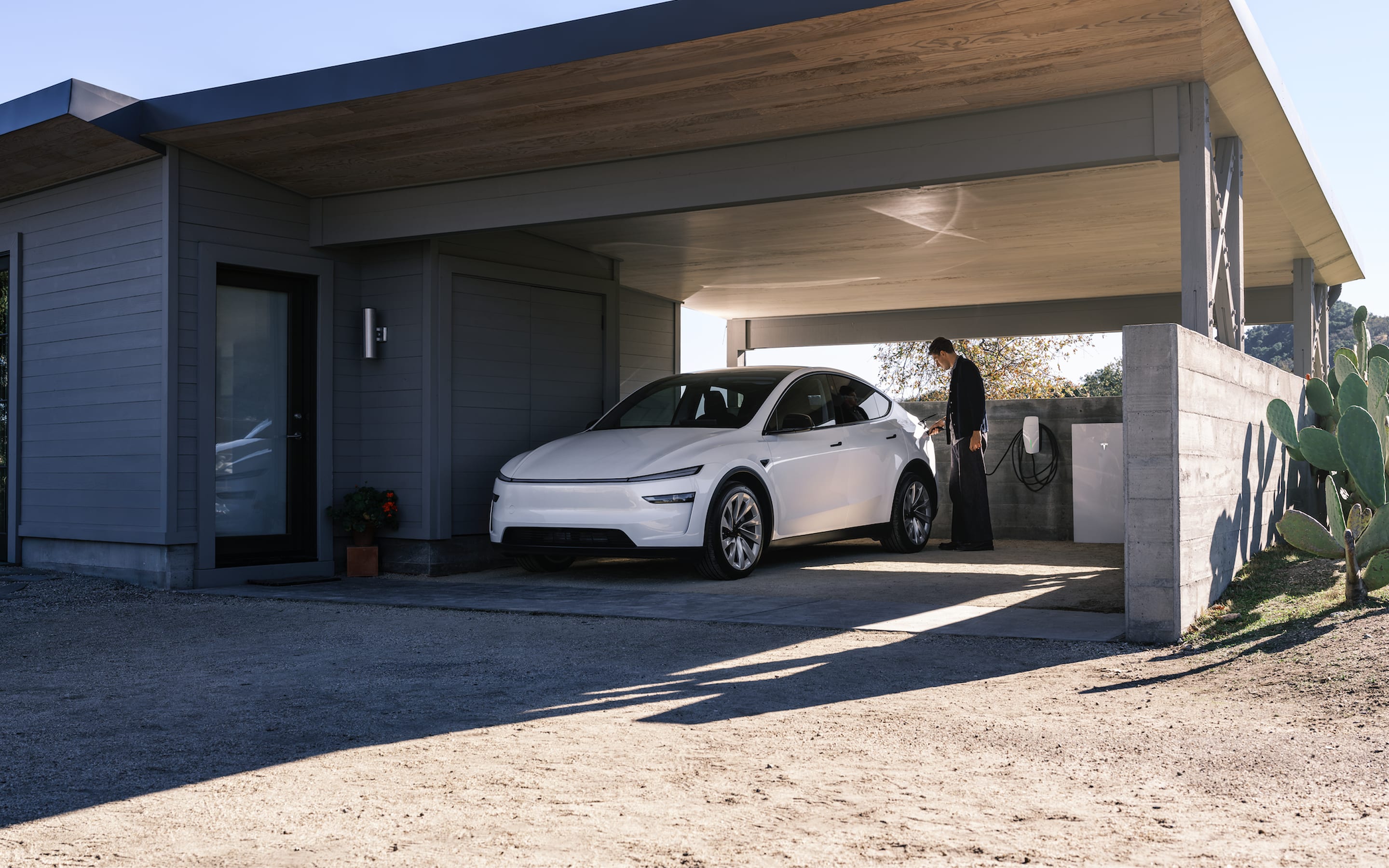 Pearl White Multi-Coat Model S charging via Wall Connector in a home's driveway