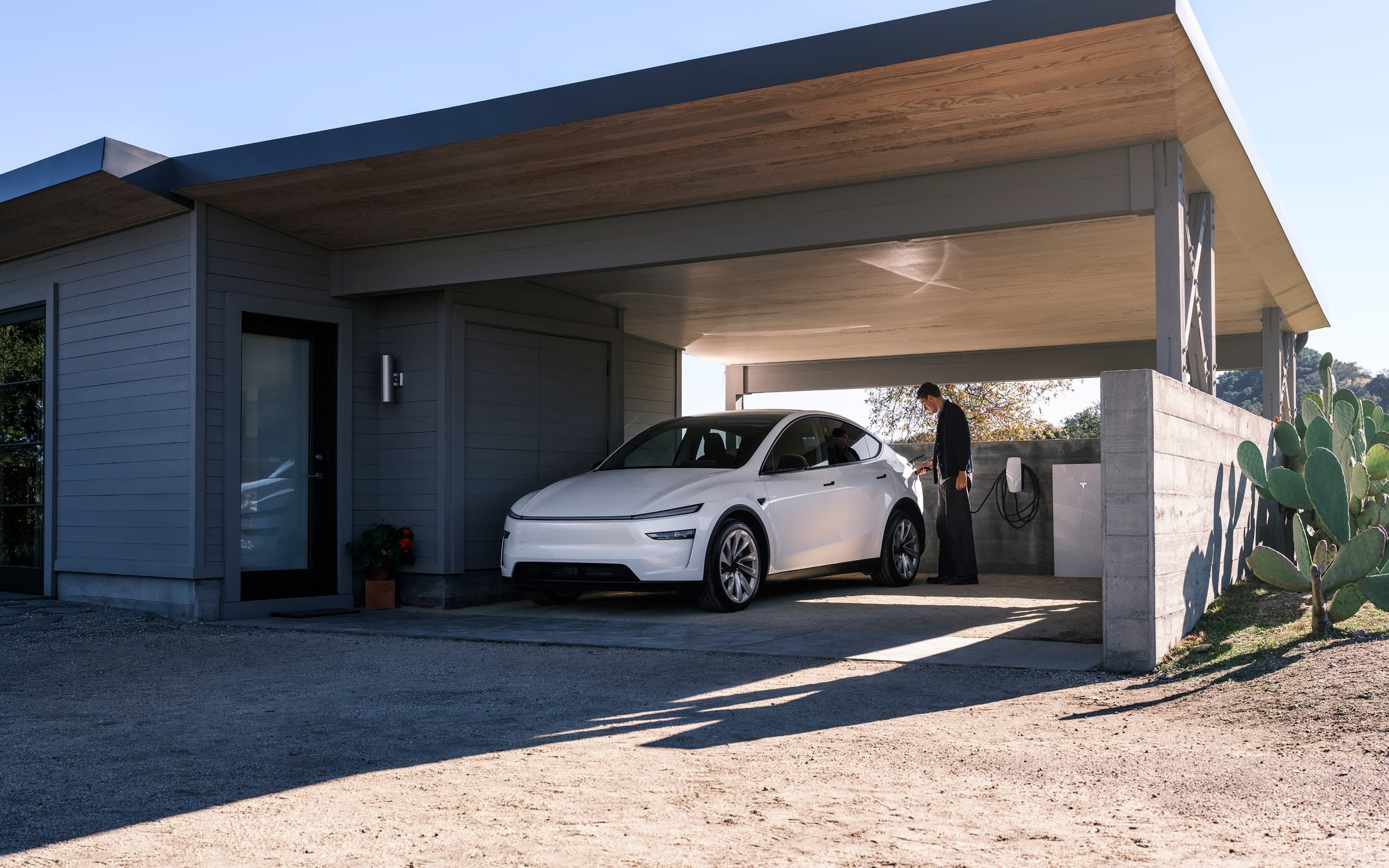 White Model Y charging at a Wall Connector in a home's driveway