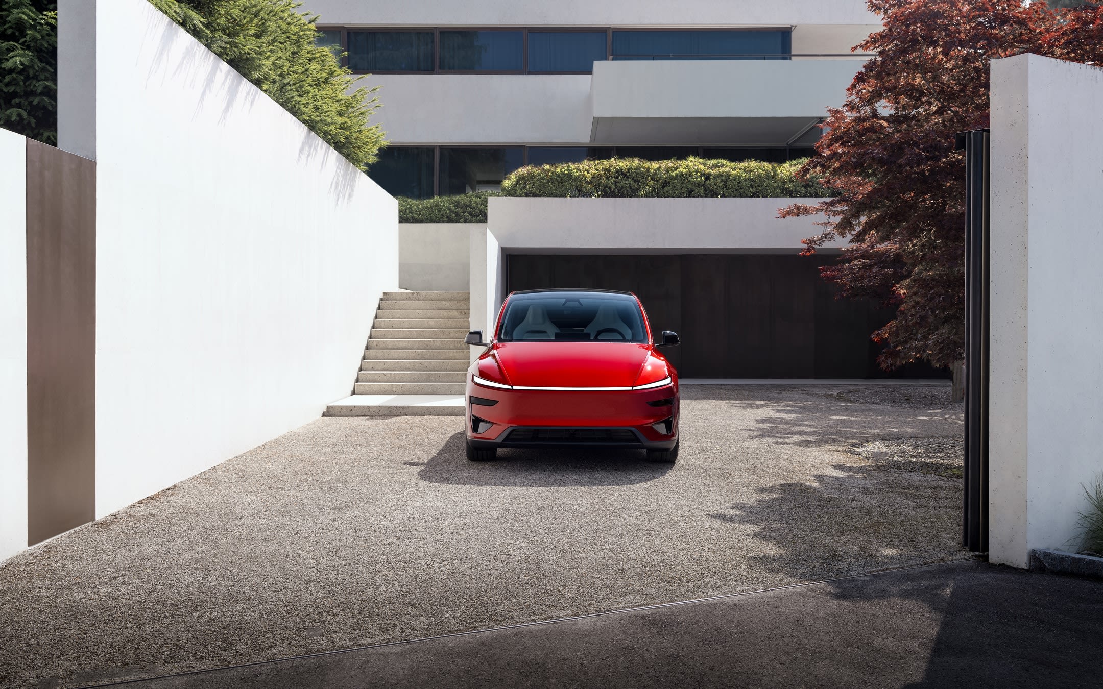 Red Model Y parked in front of a residential garage