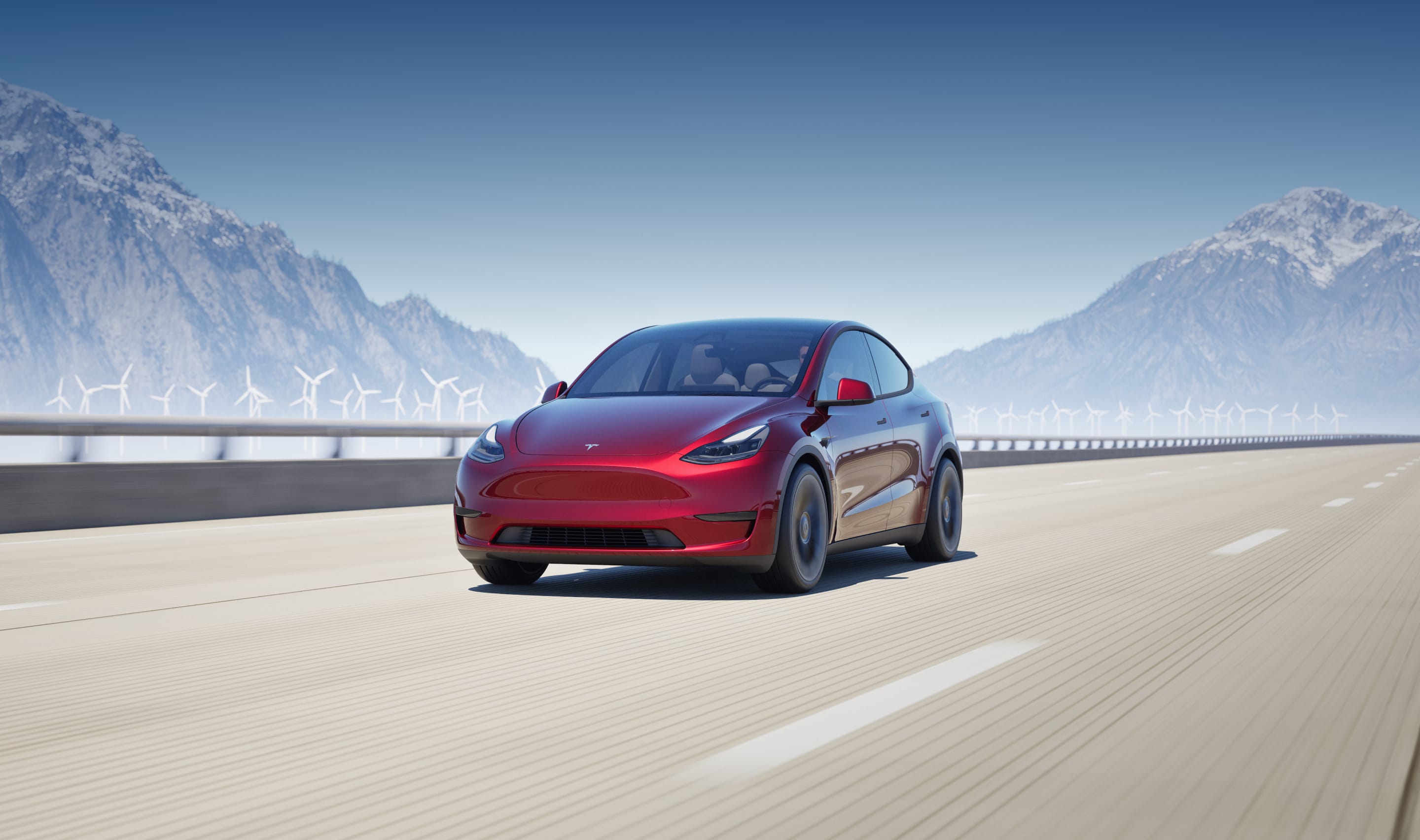 Red Model Y driving down a hillside highway