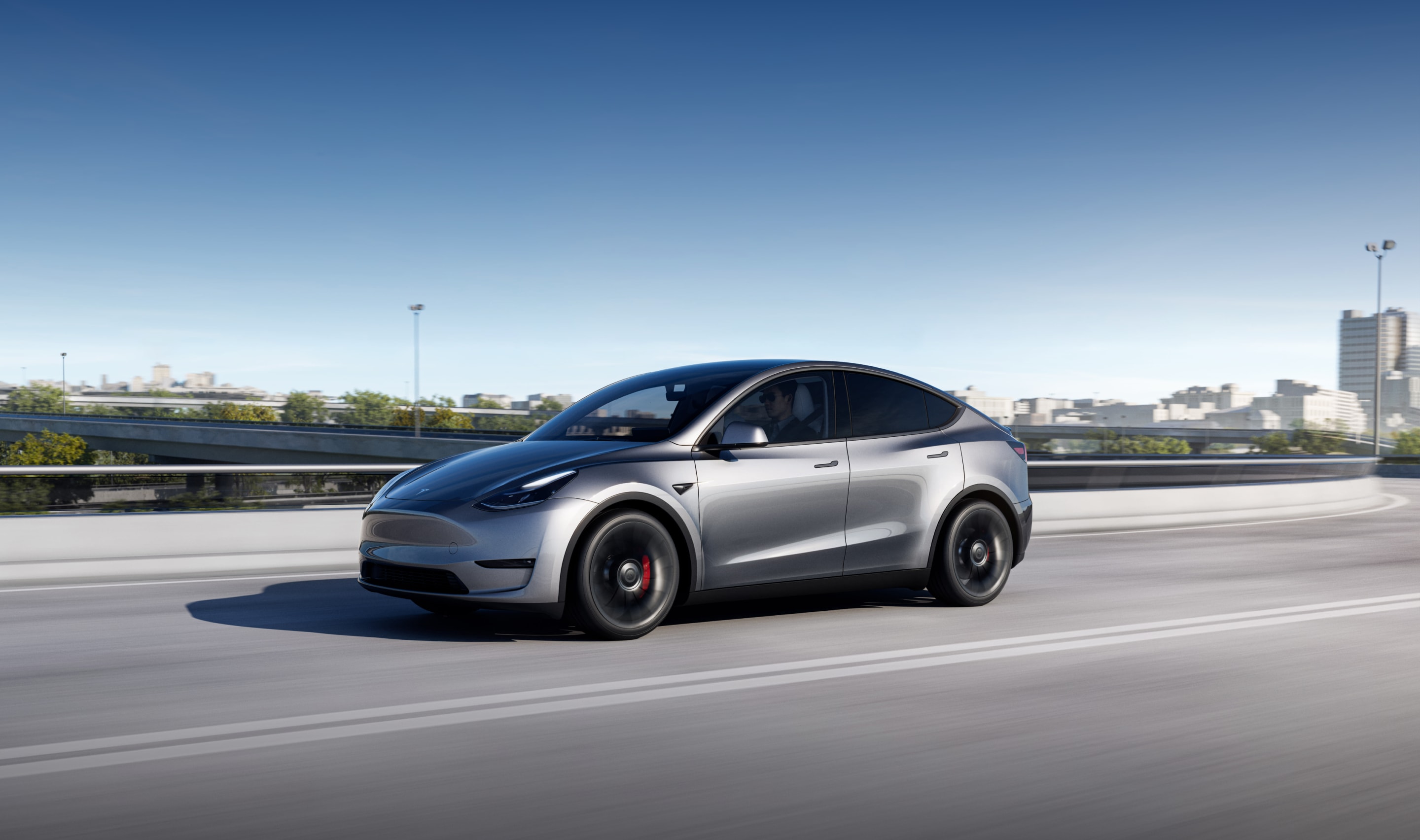 冷光银 Model Y 平稳行驶在湖边公路上