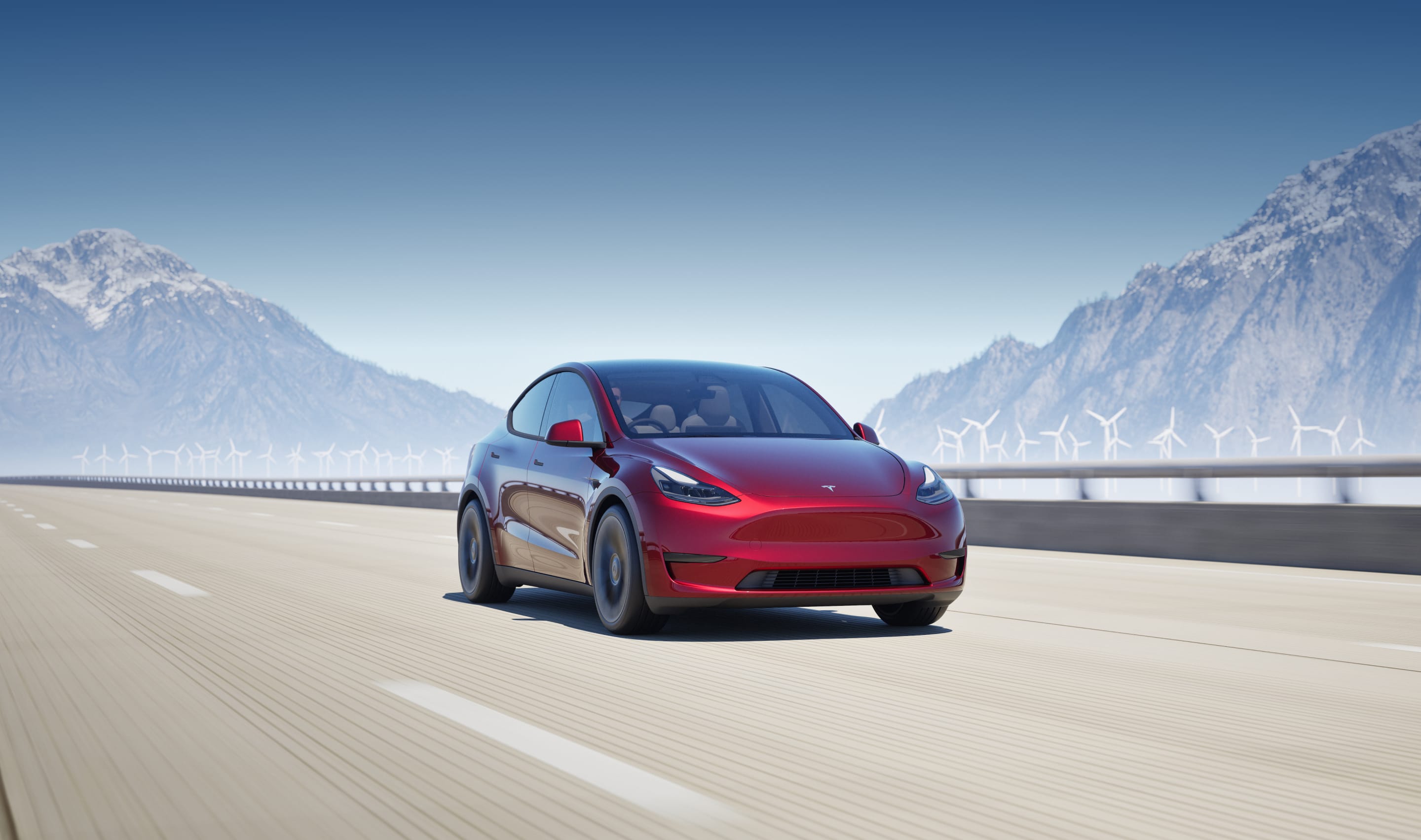 Metallic blue Model Y driving down a hillside highway