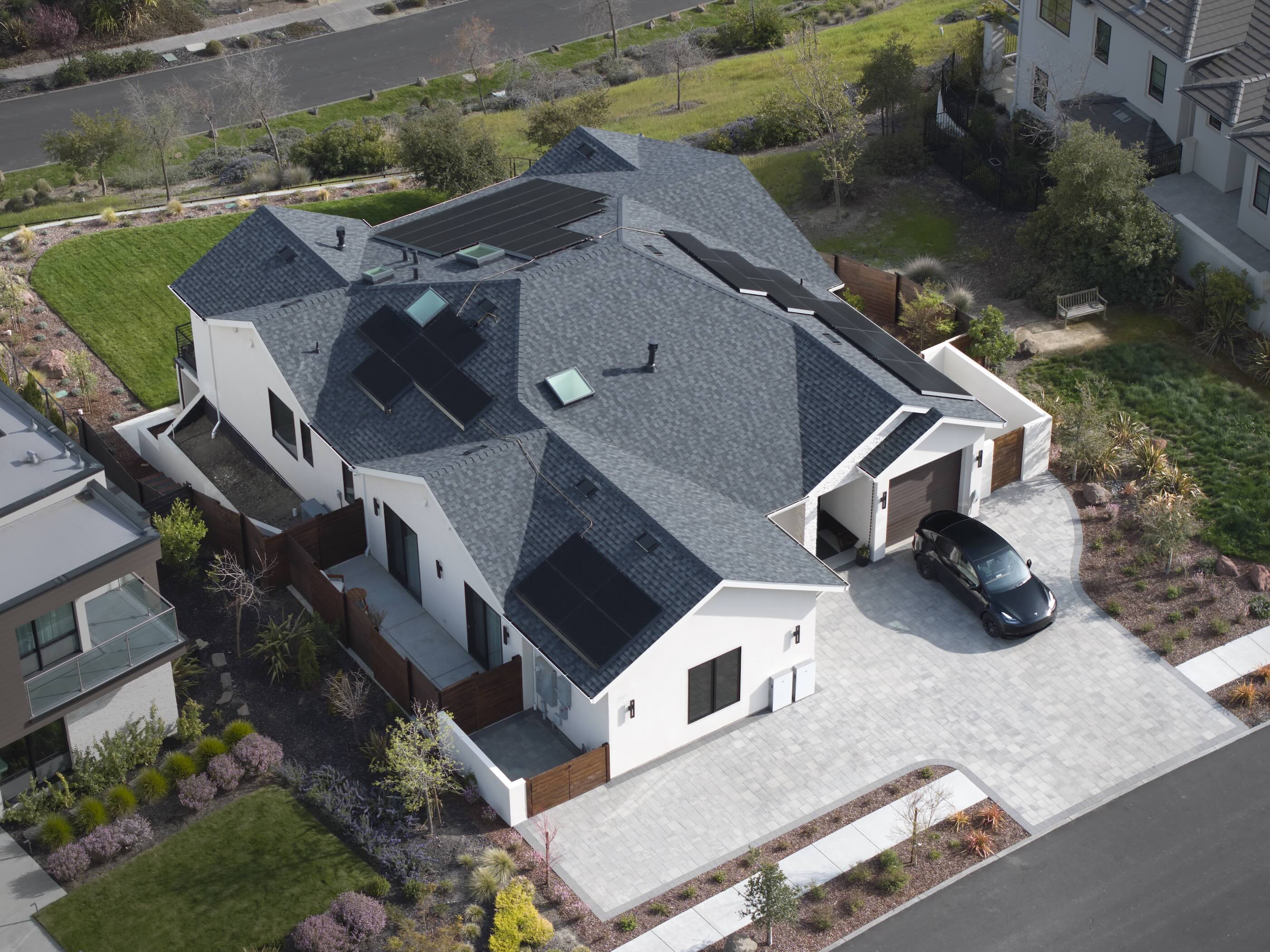 Home with solar panels installed and a Tesla vehicle parked out in the driveway
