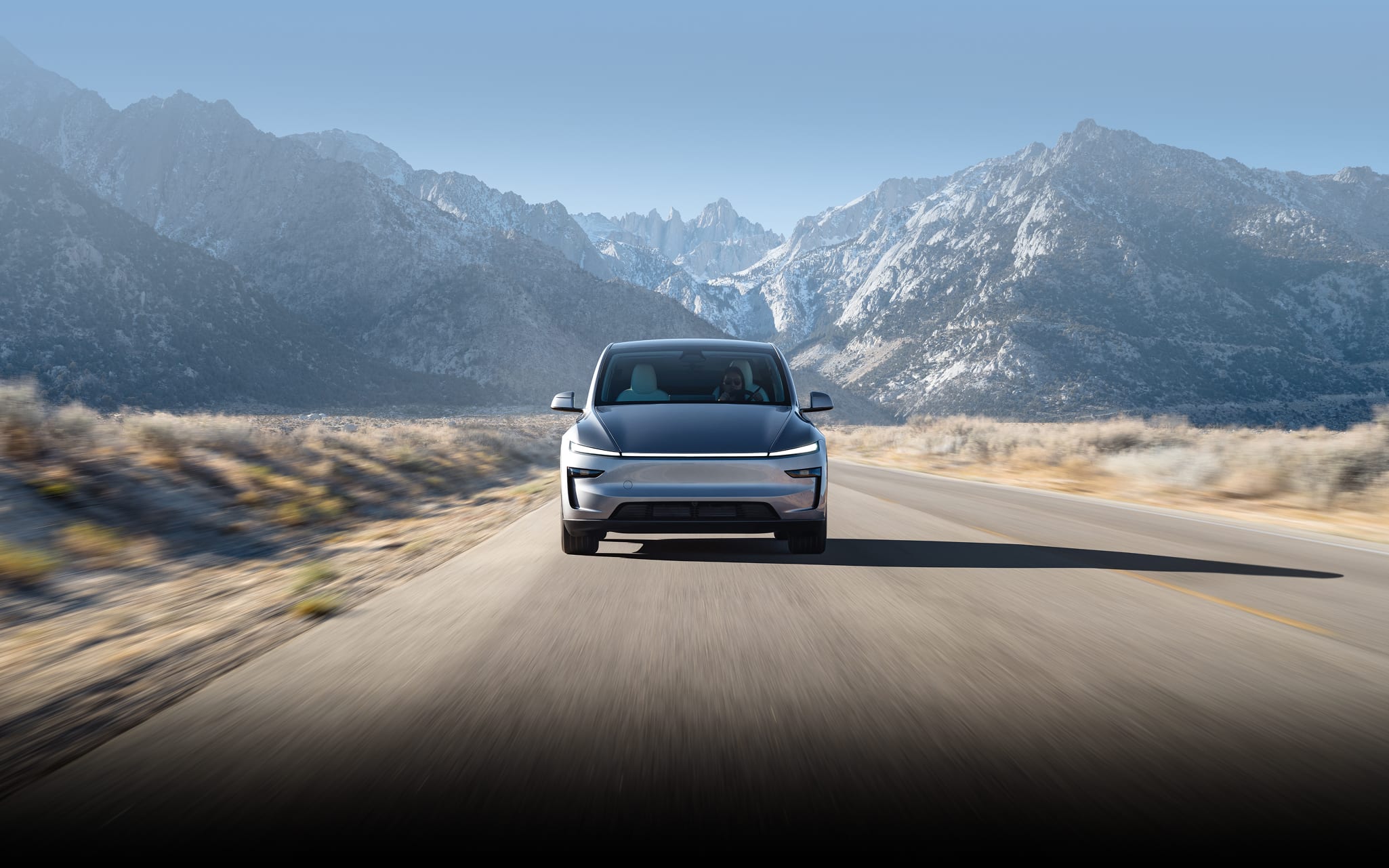 Model Y driving on road with snowy mountains in the background