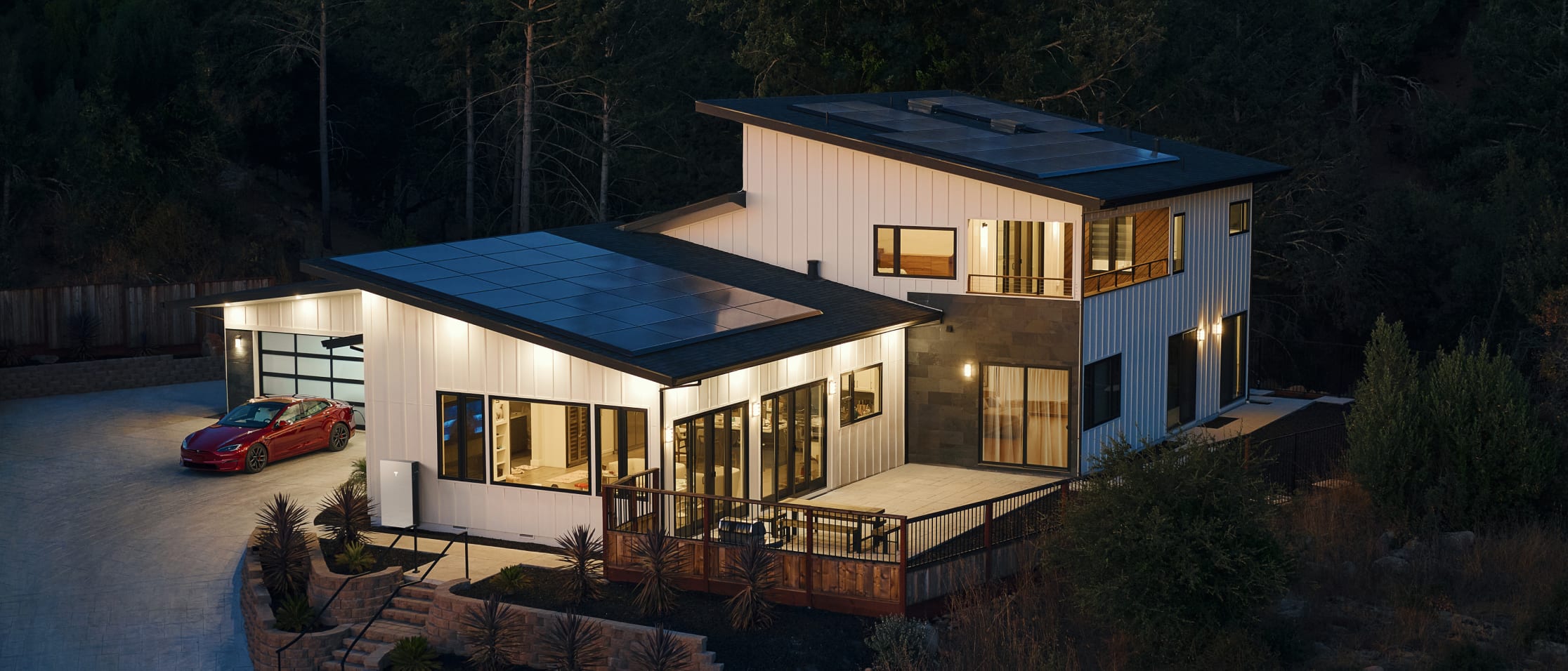 Modern home With Solar Panels and red Model S parked outside