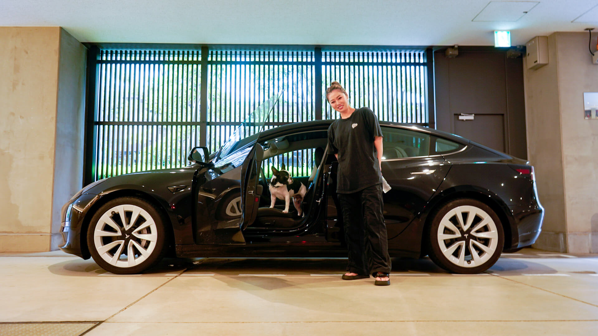 Tesla owner with her dog on left side of black model 3