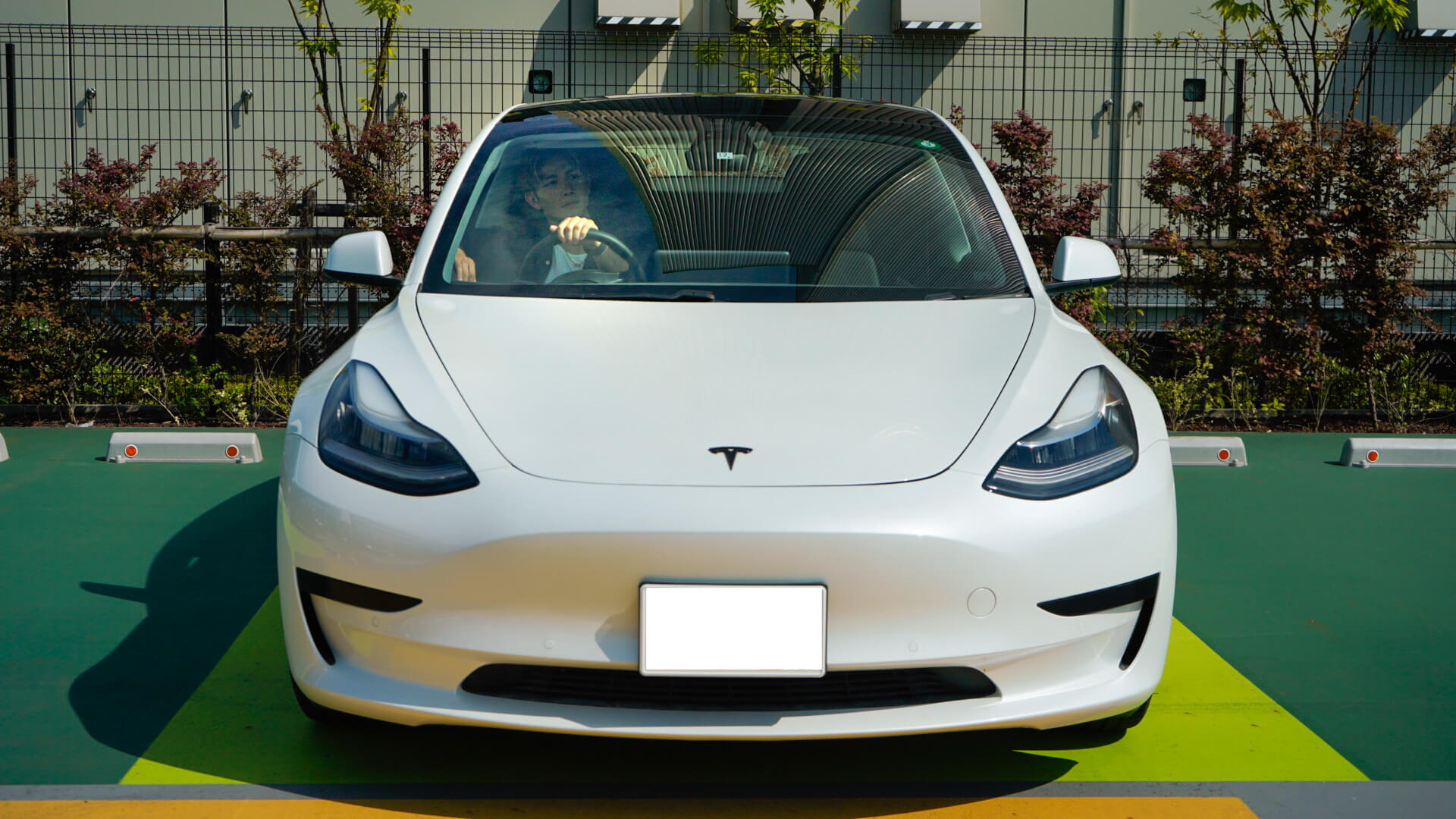 Front view of white Model 3 with a Tesla owner inside