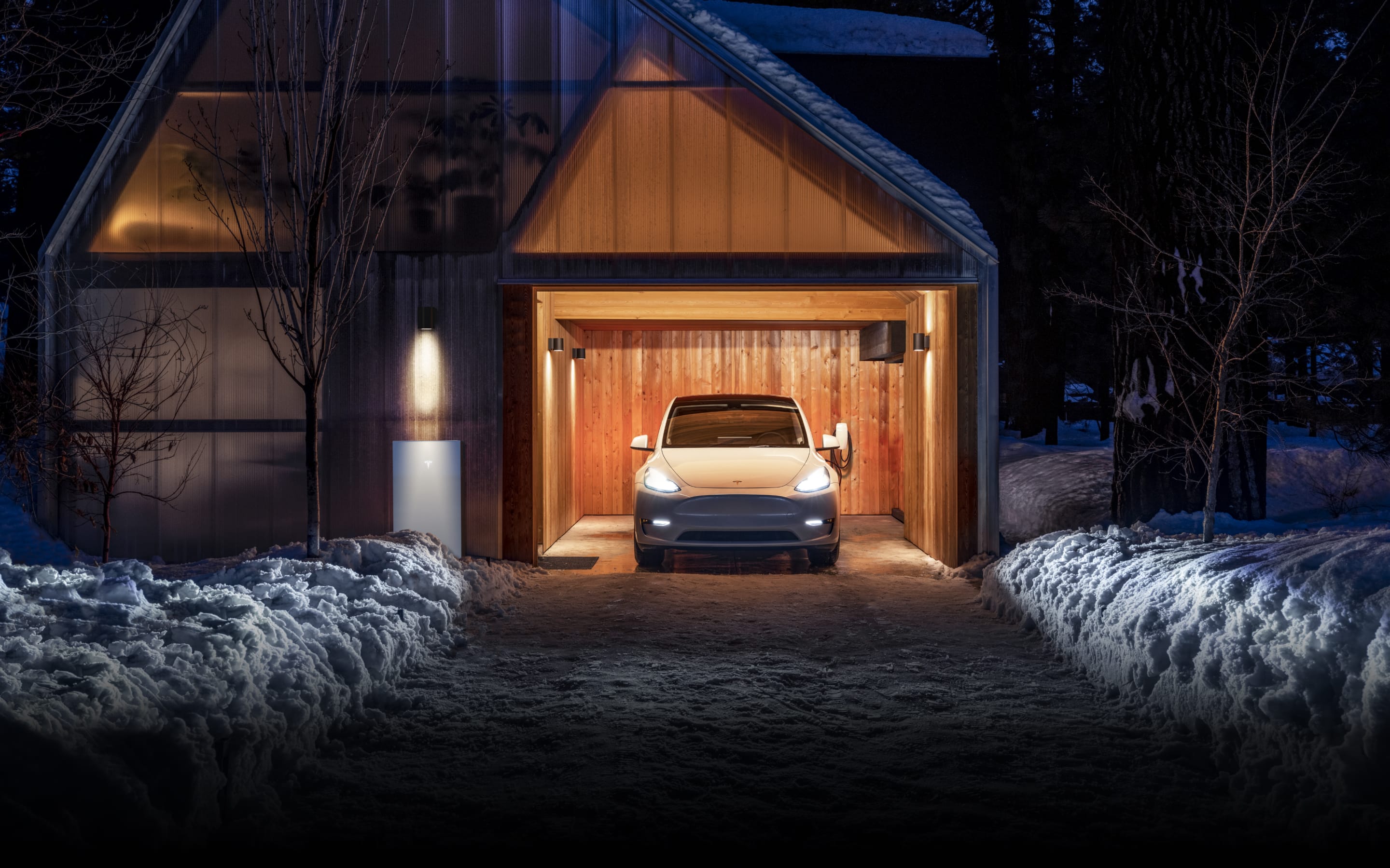 White Model Y parked in a garage with lights on and Powerwall 3 installed