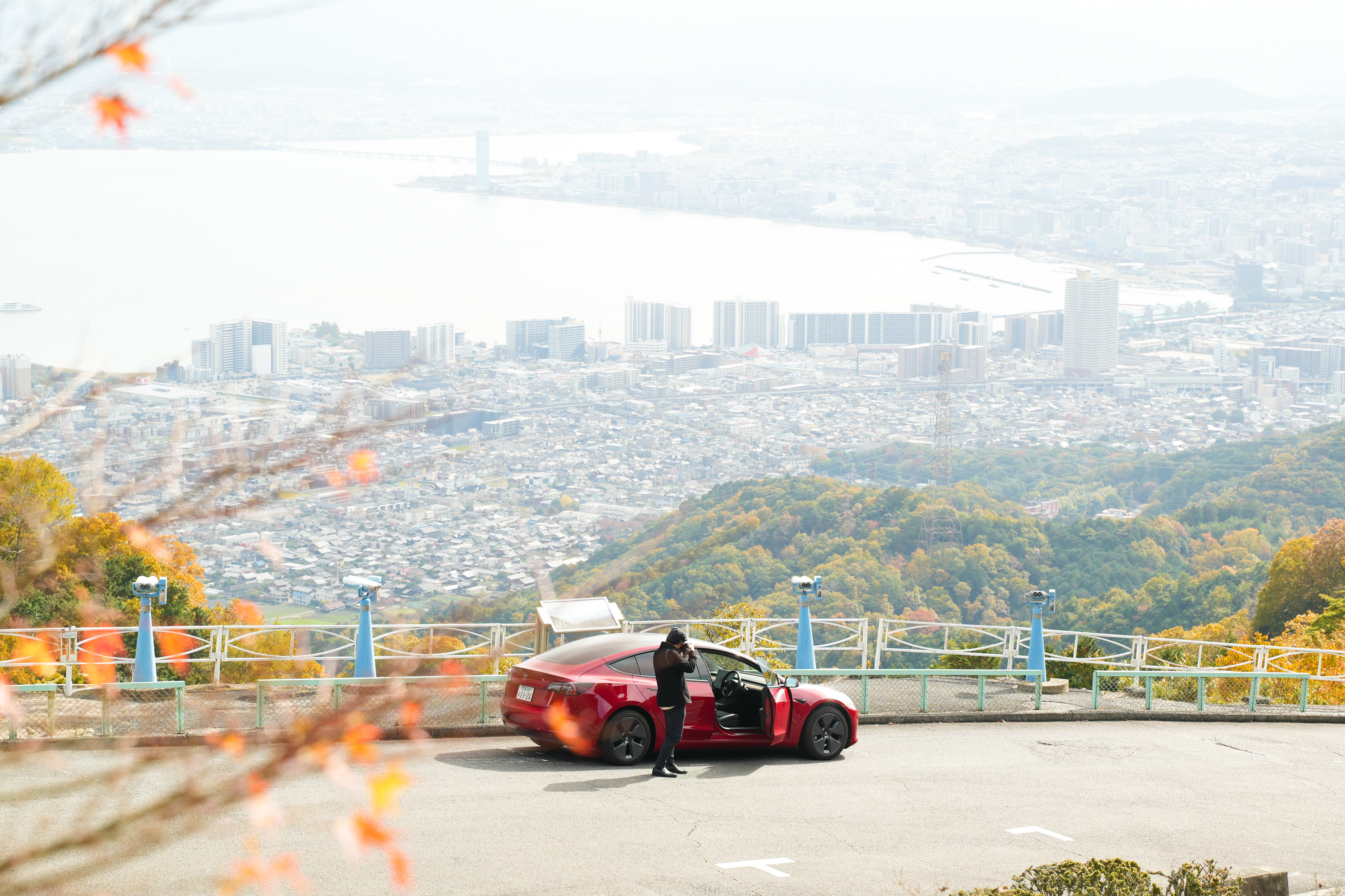 Takahiro Bessho taking a picture next to his red Model 3
