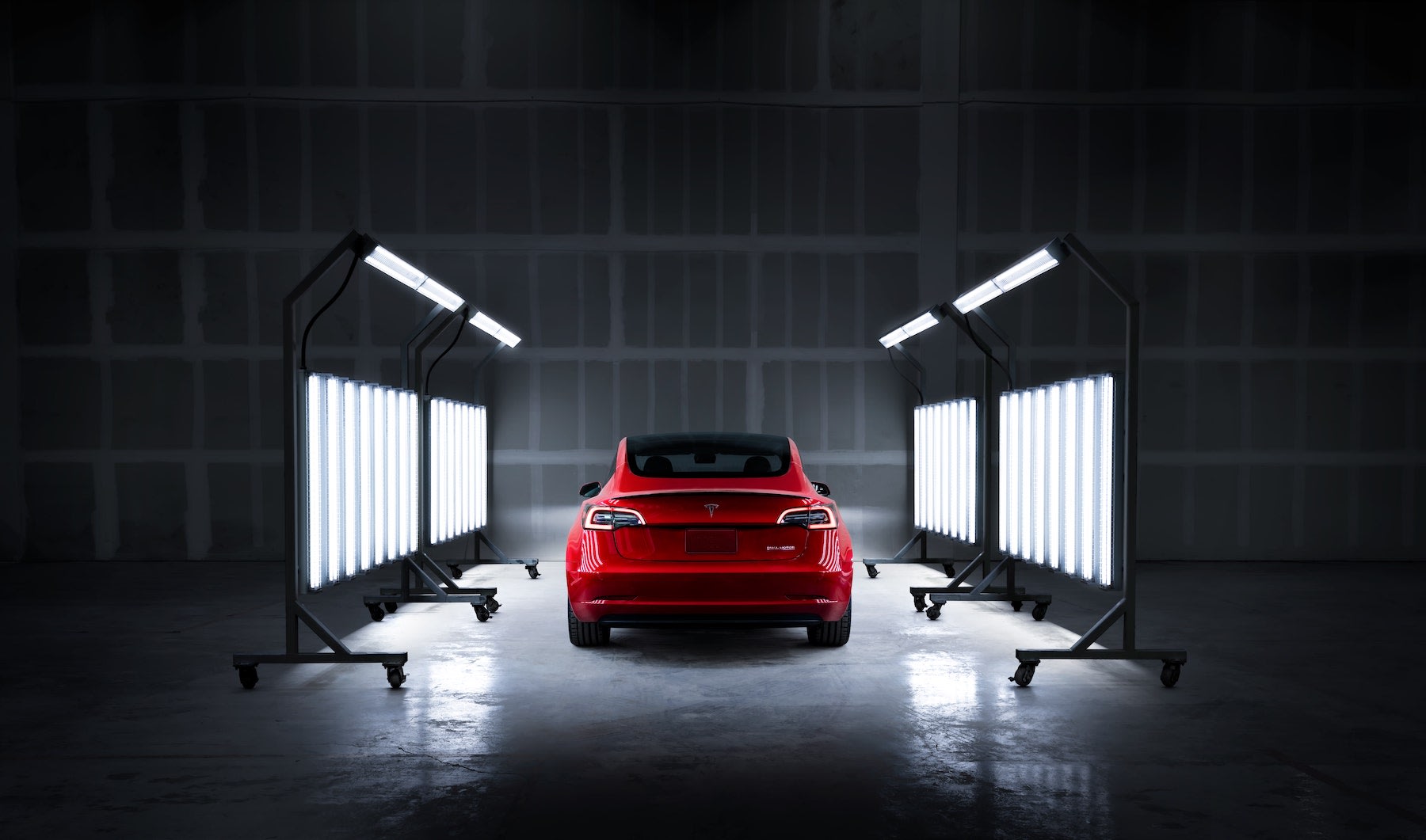 Lights focused on a red Model 3 in dark setting