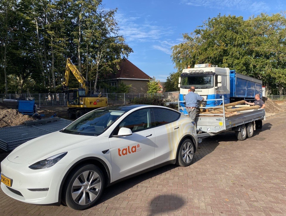 Pearl White Model Y with Tala Logo towing a trailer with wood