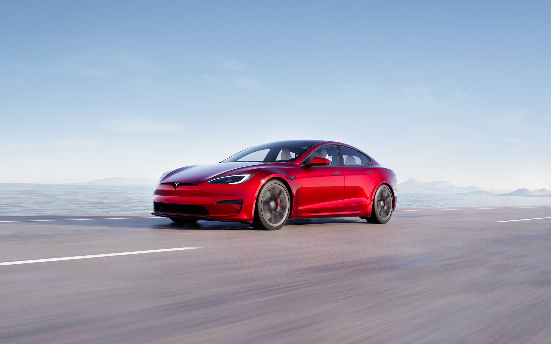 Model S בצבע אדום בהאצה על כביש מהיר מוגבה	