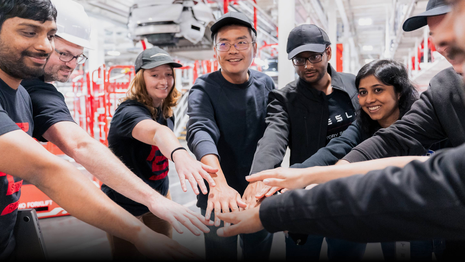 Service employees (both male and female) putting their hands together and laughing while in the workplace