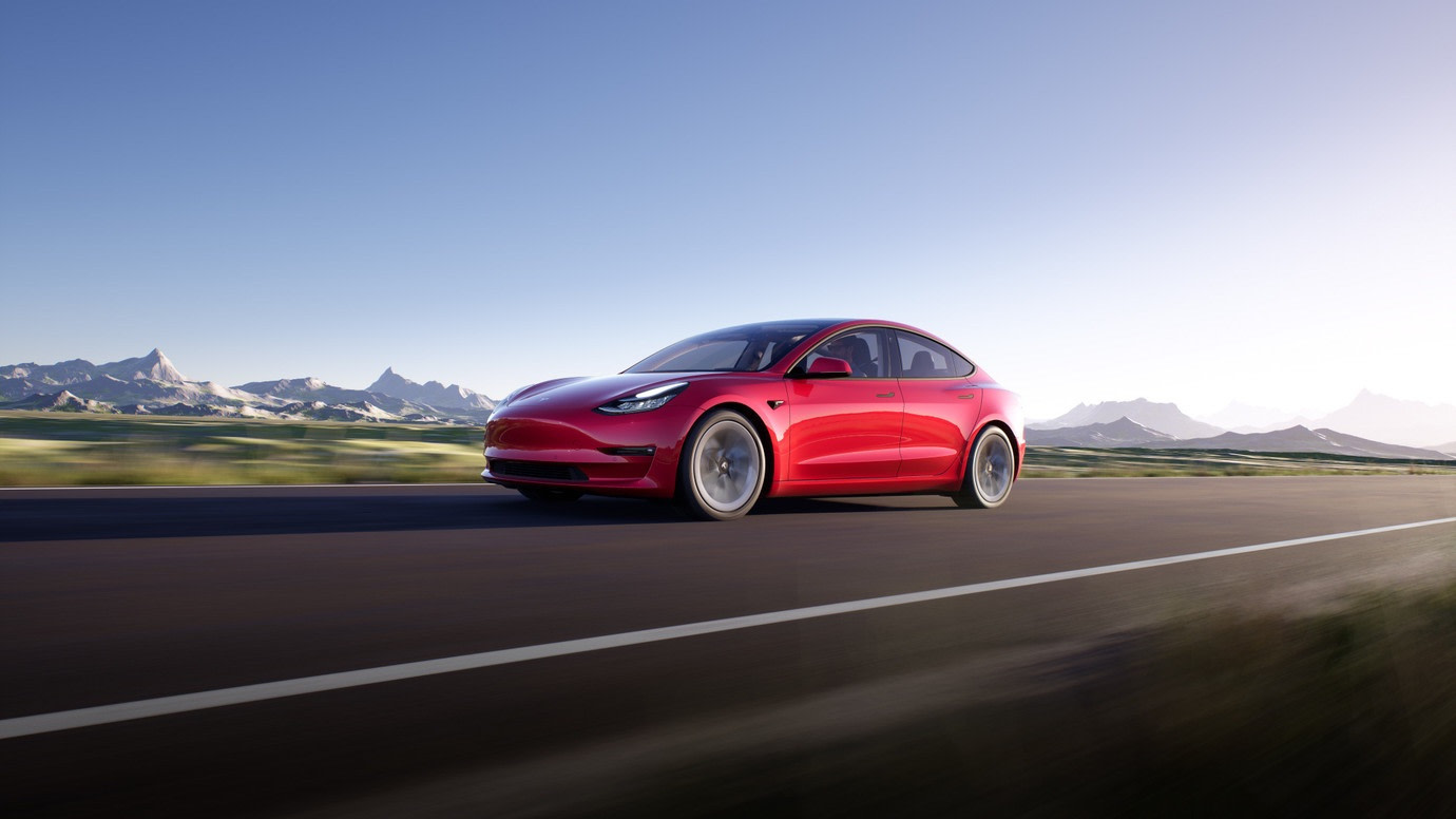 Red Model 3 driving on mountainous road