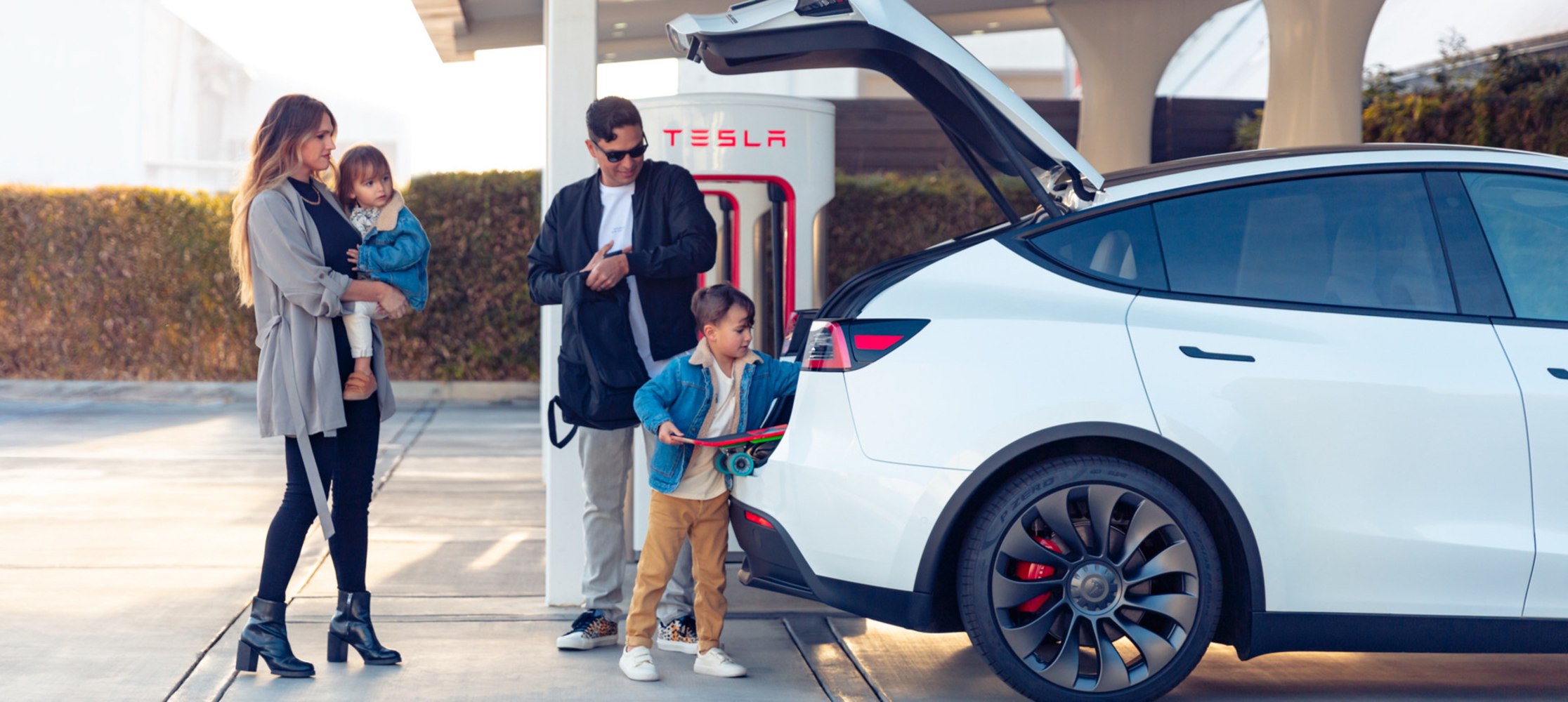 Obitelj zajedno puni vozilo Tesla. 