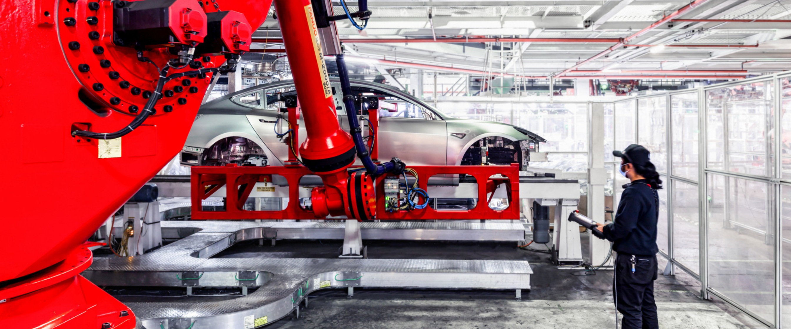 Zaměstnanci a stroje ve výrobě společnosti Tesla