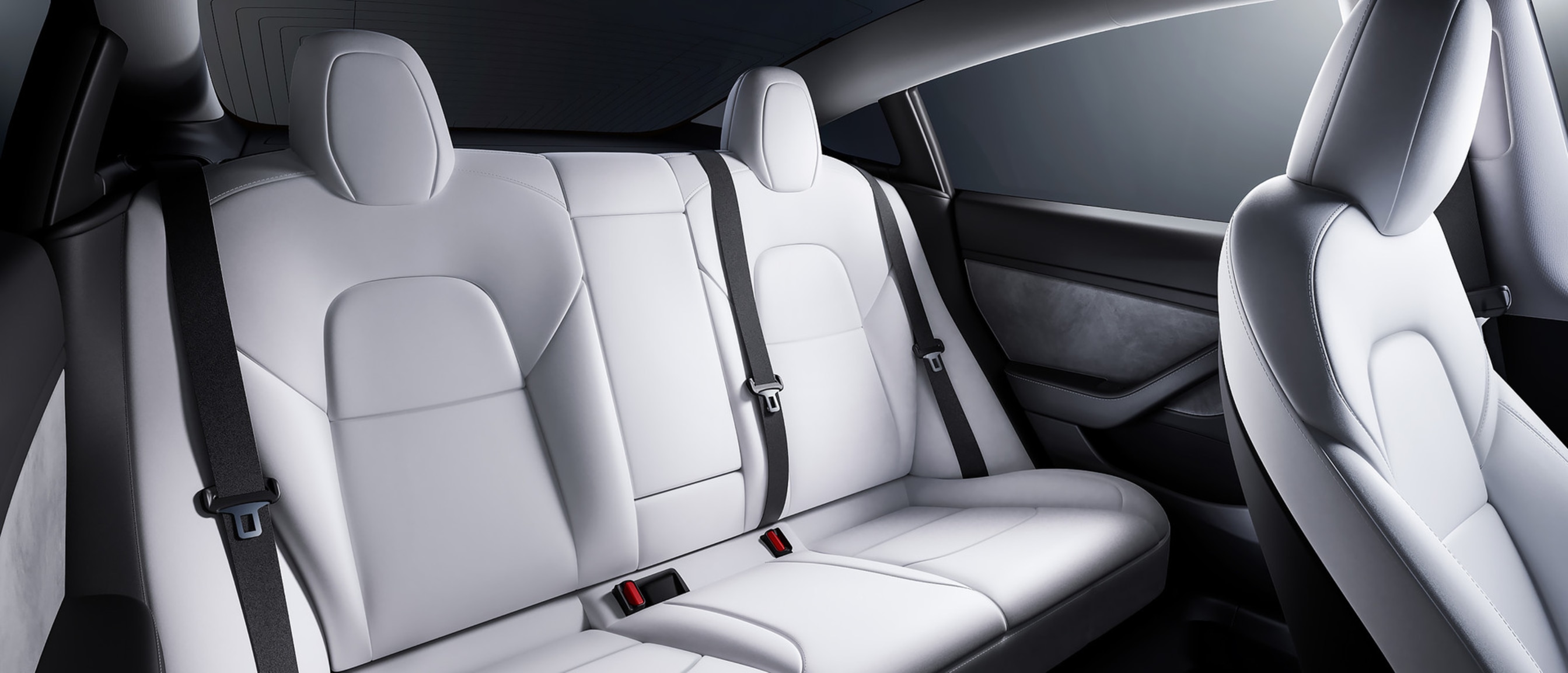 View of the spacious backseat of a Model 3 with white interior