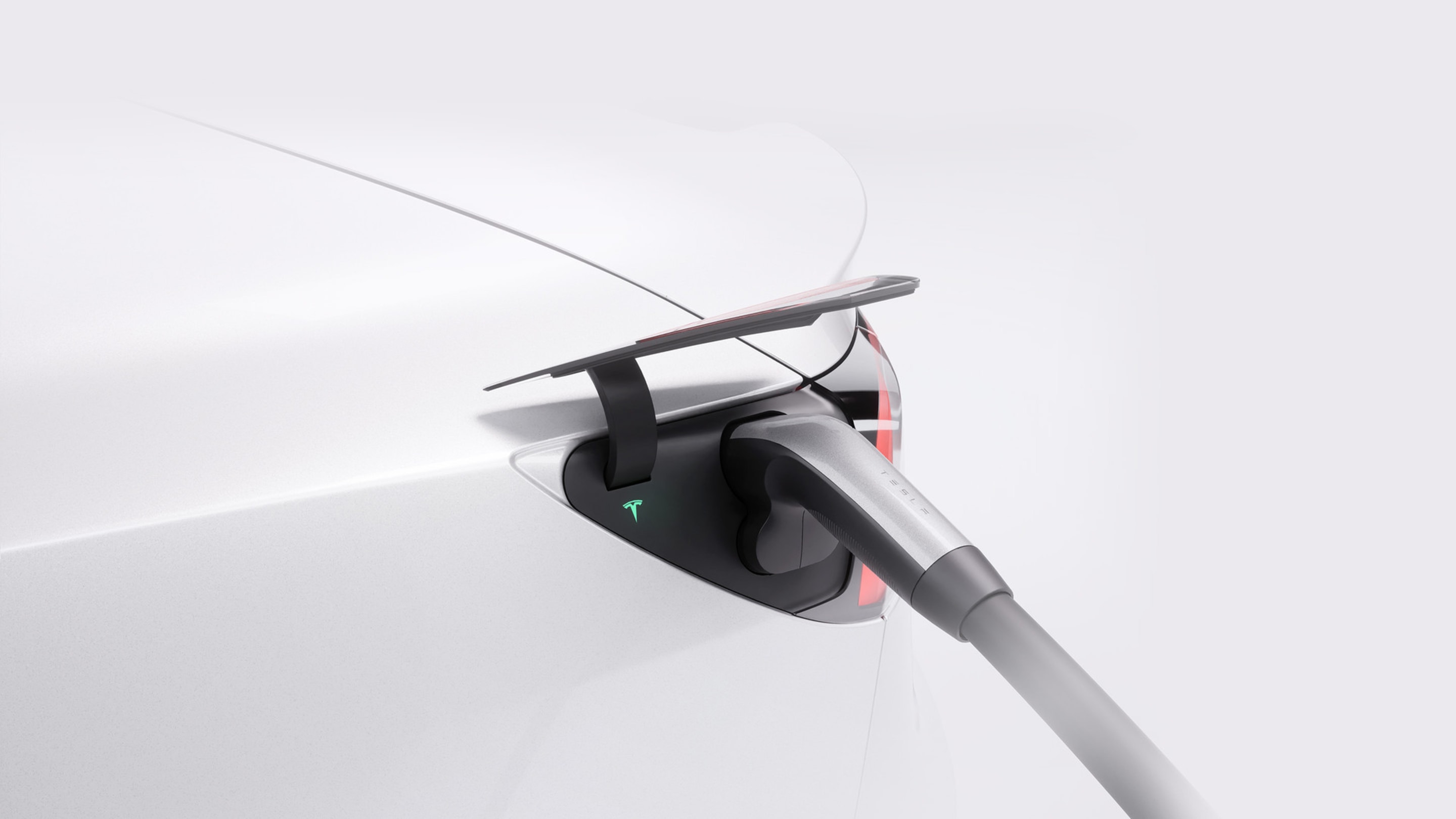 Vista ravvicinata di un Supercharger collegato allo sportello di ricarica di una Tesla