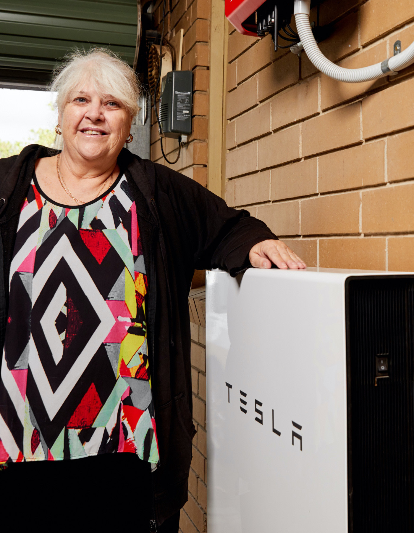 A customer of South Australia Virtual Power Plant standing next to Powerwall
