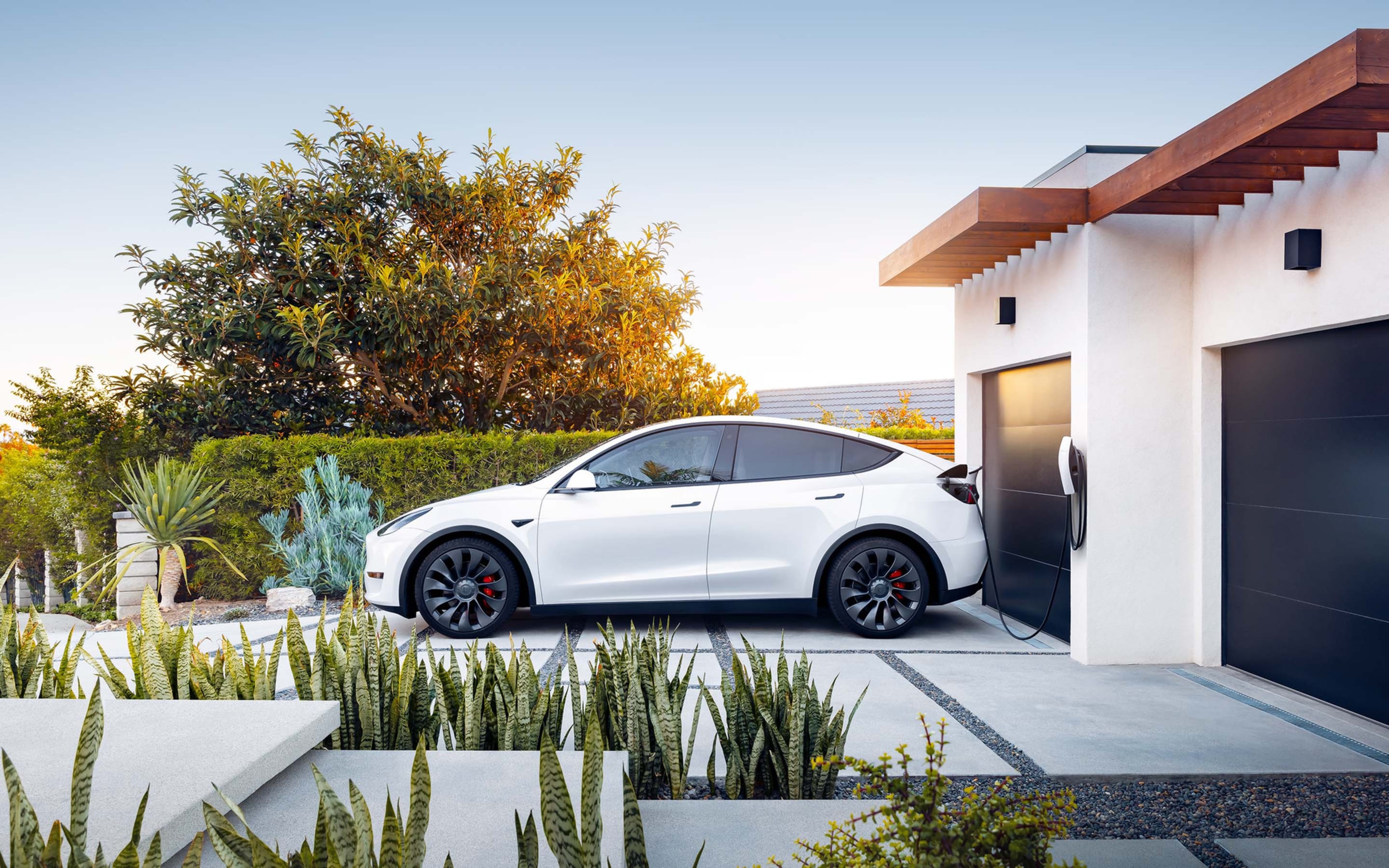 White Model S in a carport charging via Gen 3 Wall Connector