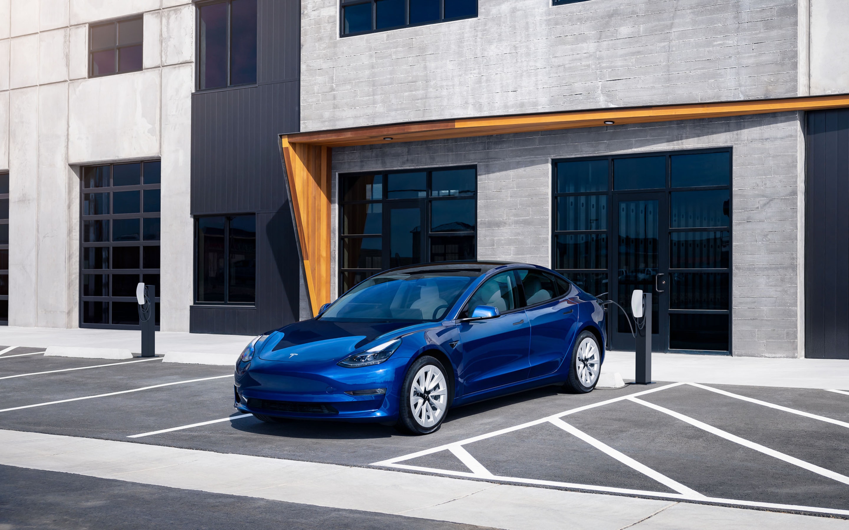 Blue Model 3 charging in front of a building