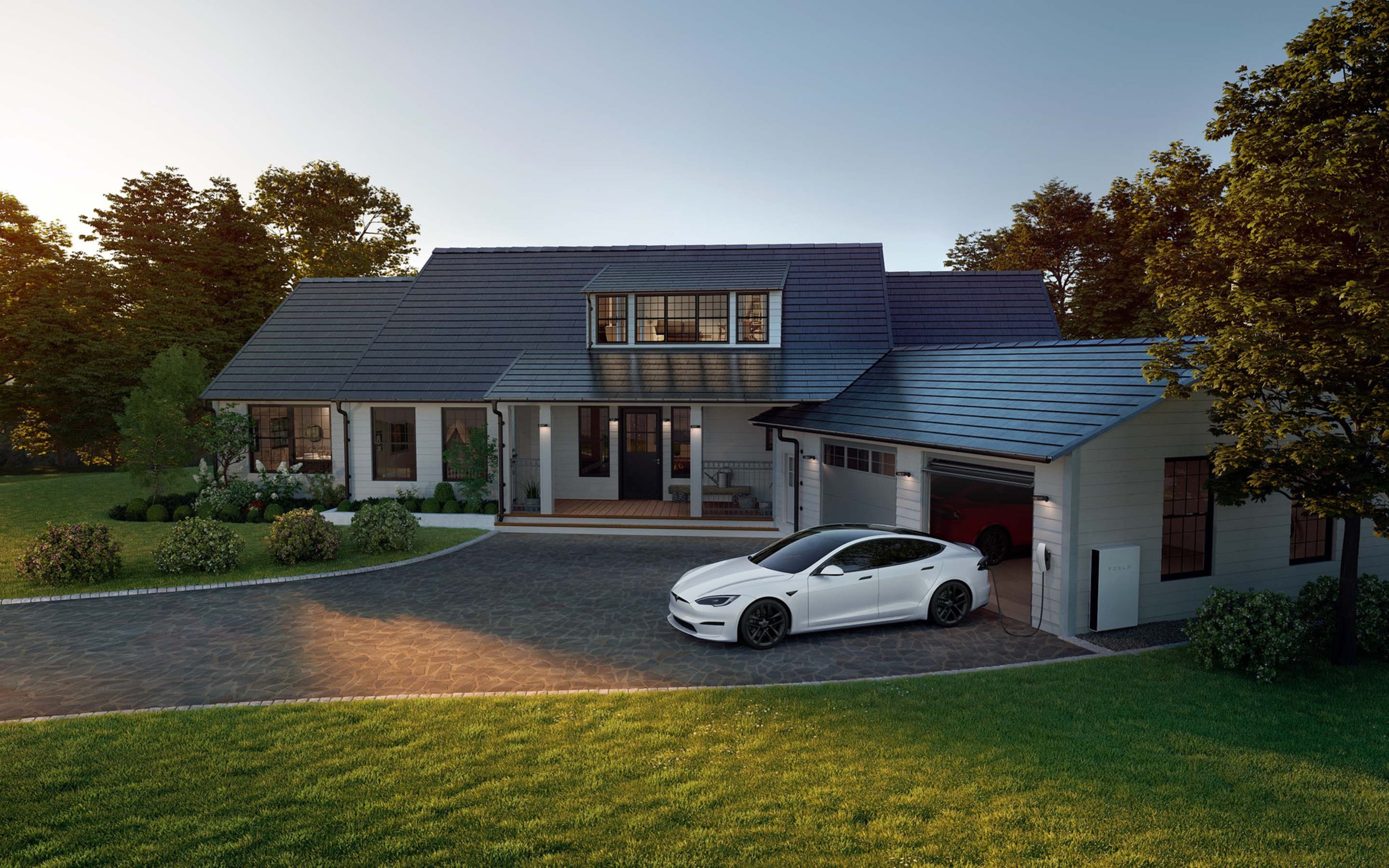 Pearl White Multi-Coat Model S lader via Wall Connector i oppkjørselen til et hjem