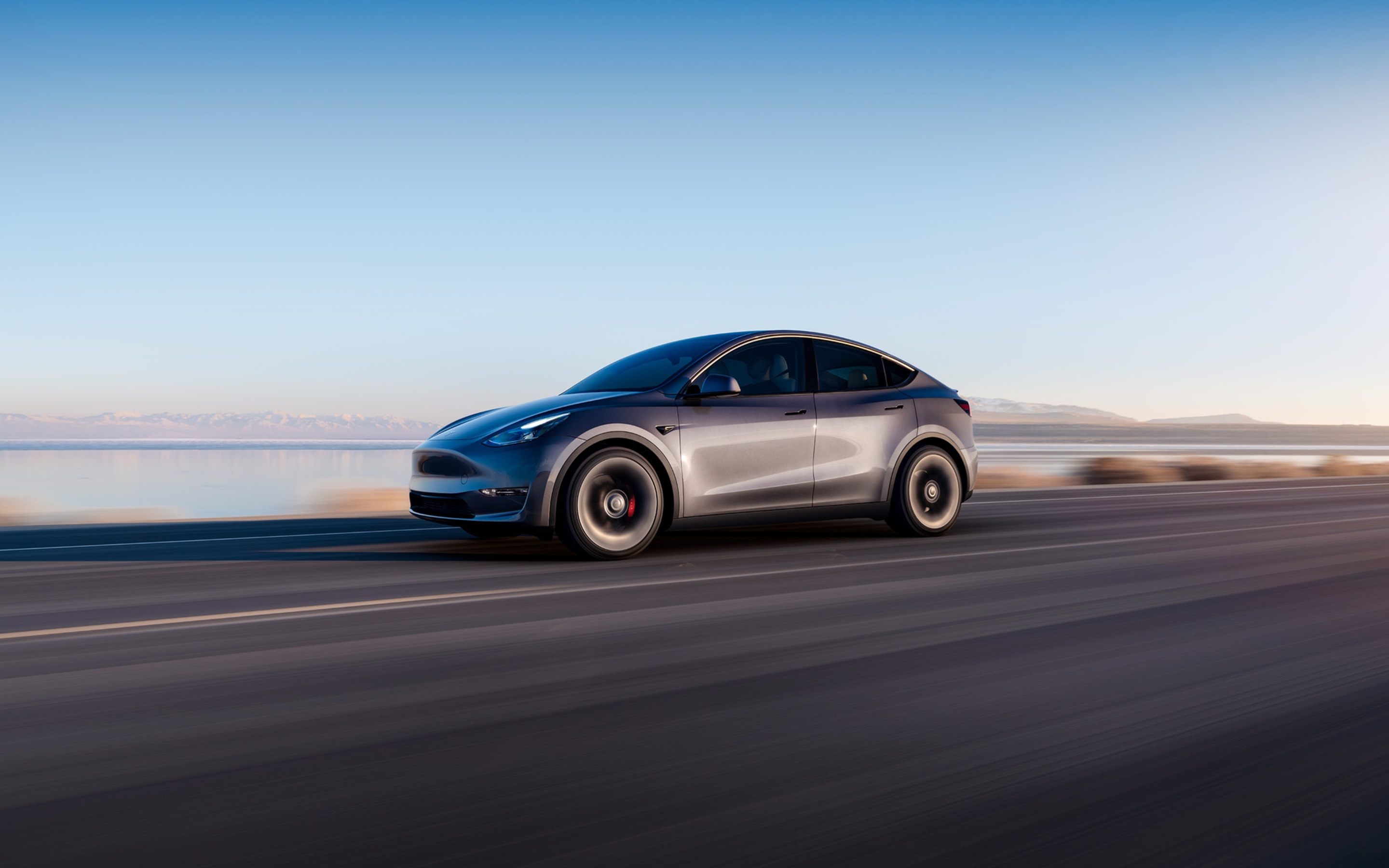 Midnight Silver Metallic Model Y driving down a lakeside road