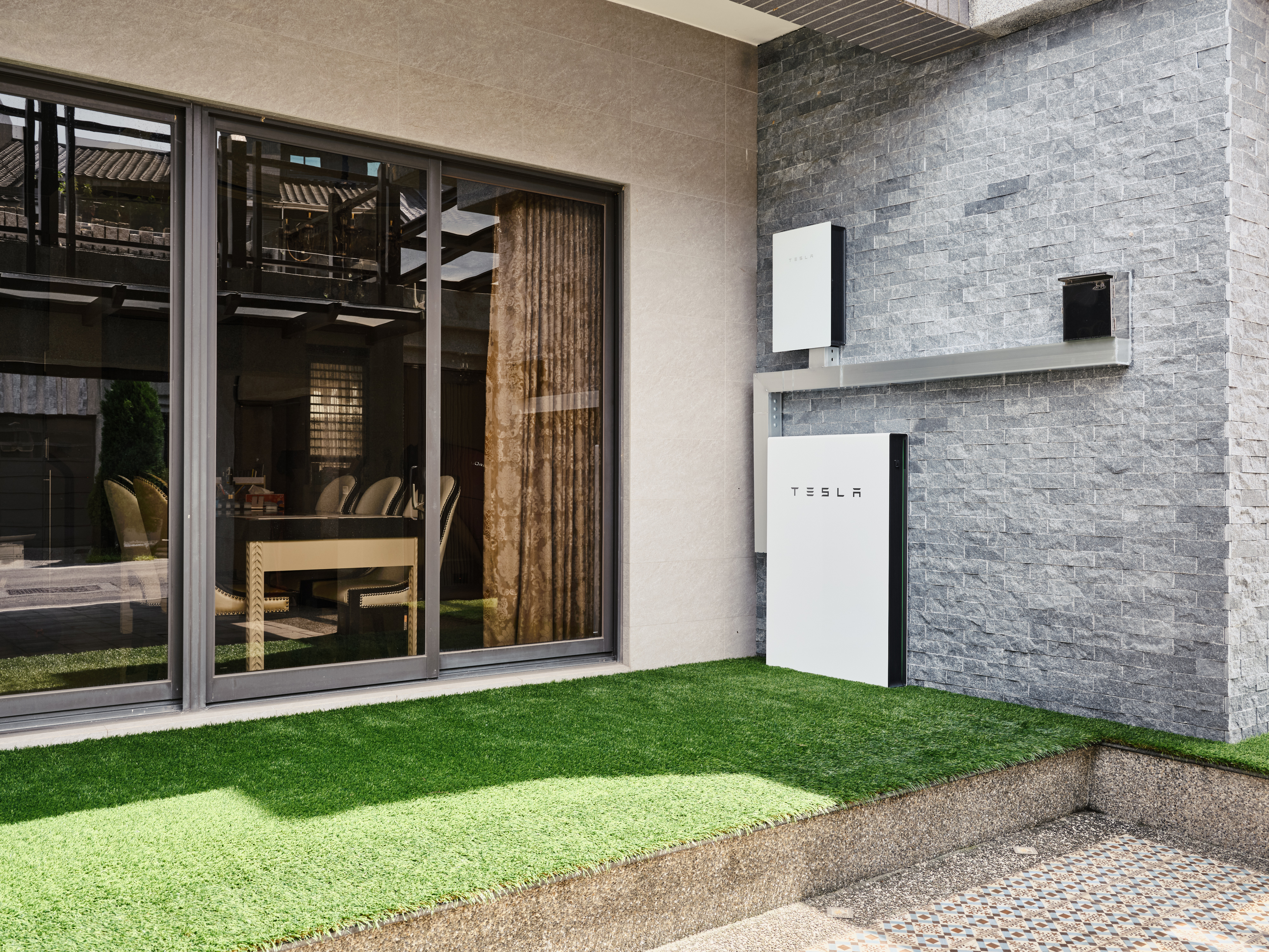 安裝在石牆上的白色 Tesla Powerwall